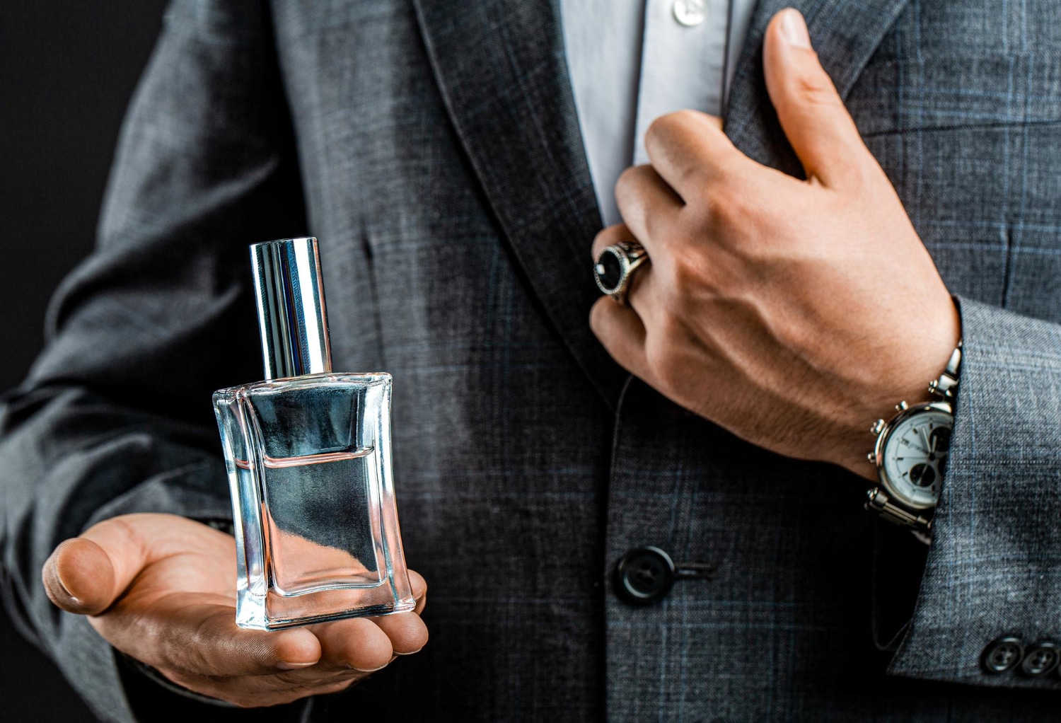 Mężczyzna trzymający w ręku perfumy męskie do 200 zł