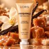 Złocistobeżowa tubka kremu do rąk Loris Frequence Caramel Gourmand U-29 obok kostek karmelu i jasnego kwiatu.