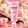 Różowa tubka kremu do rąk Loris Frequence Sweet Marshmallow K450 na tle pianek marshmallow i jasnych kwiatów.