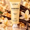 Jasnożółta tubka kremu do rąk Loris Frequence Vanilla Soft U-26 na tle jasnych kwiatów i ciemnych lasek.
