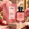 Różowy, fasetowany flakon Loris Secret Bloom z czarną nakrętką obok różowego pudełka.